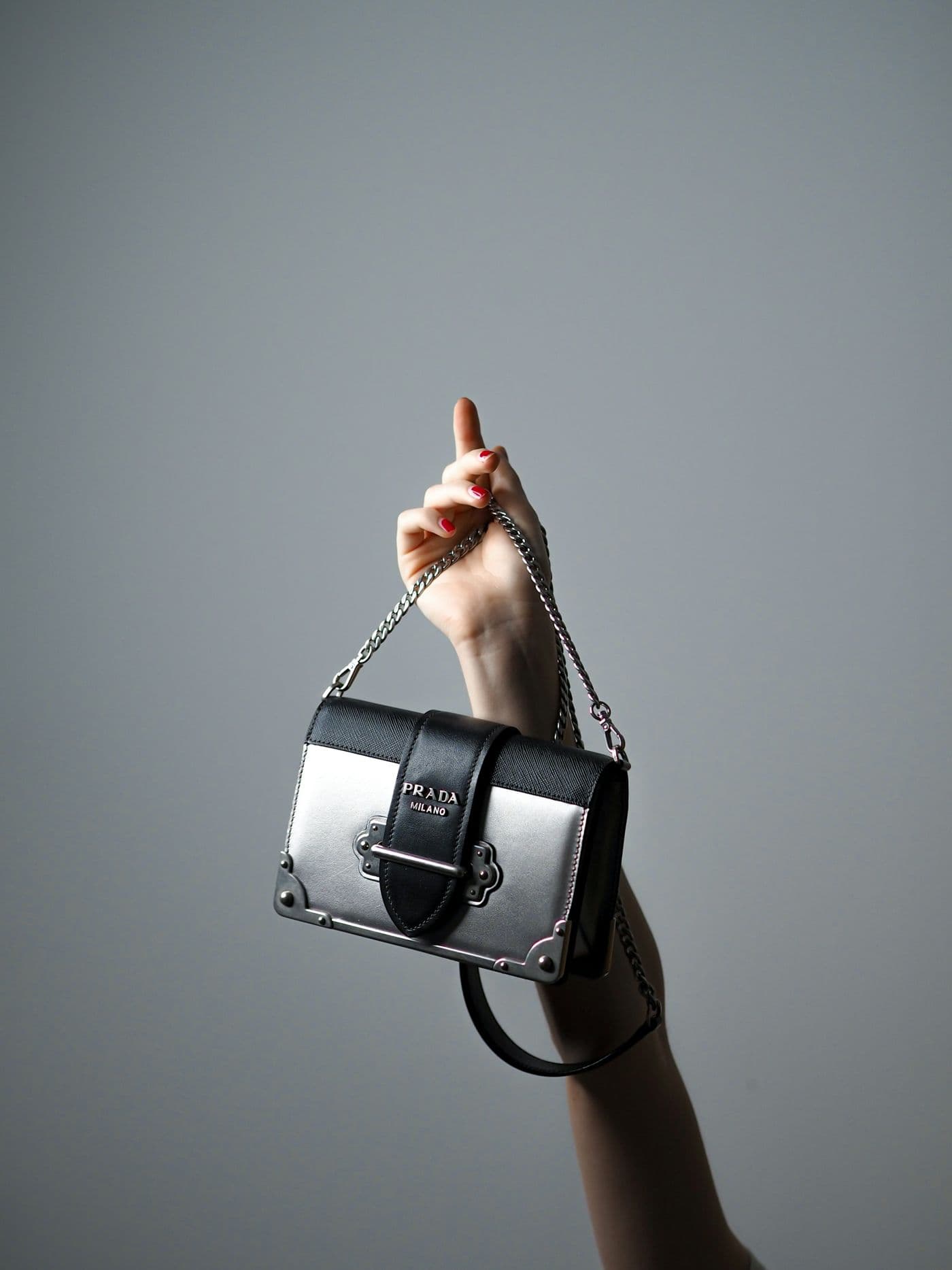 A hand holding up a black handbag